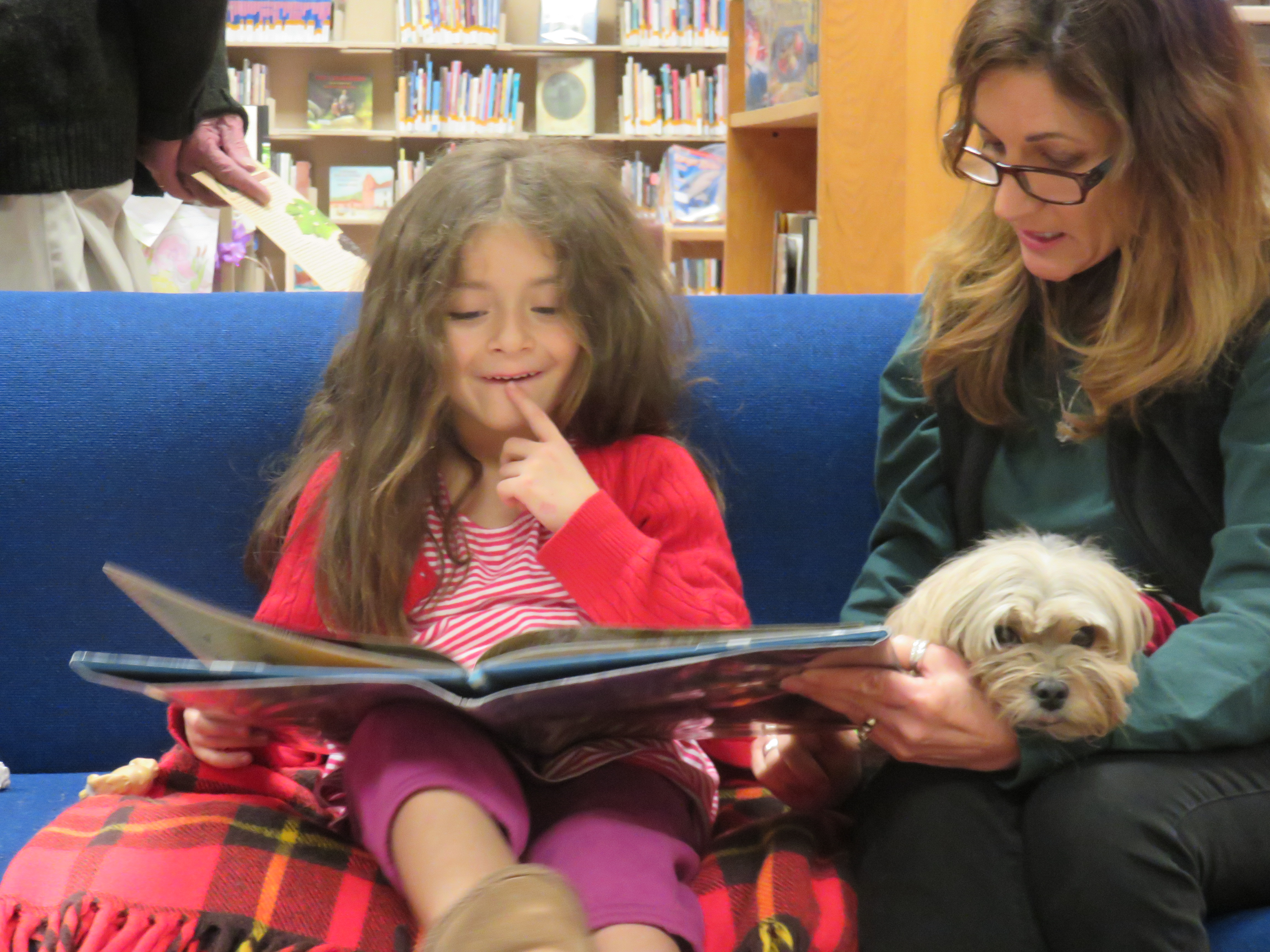 Young girl reading to a small dog.