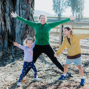 Photo of Ozlem with arms outstretched and two kids standing on either side.