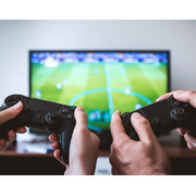 Photo of hands playing Playstation with TV in background