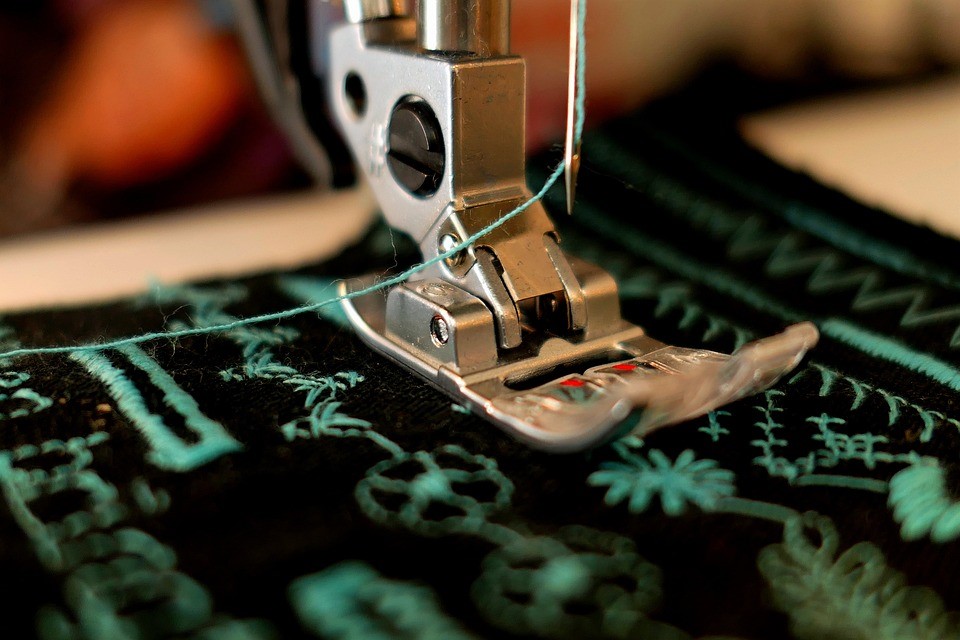 Needle of sewing machine hovering over fabric.