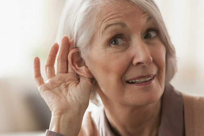 Photo: Older adult woman gesturing with hand by ear