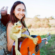 Photo of performer Melita holding a guitar and a frog puppet.