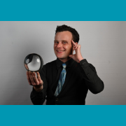 Photo of magician Colin Rickets in a black shirt and tie.